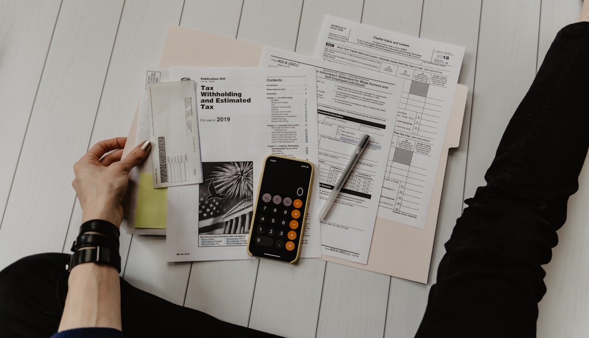 Accounting paperwork, a calculator and a pen laid out on a desk